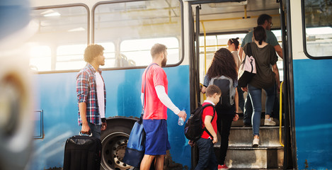 Group of people is standing in line and waiting to get in a bus.