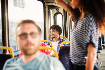 Charming Afro-American man is looking through the bus window and smiling.