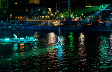 Hanging acrobats just above the water in green ligth