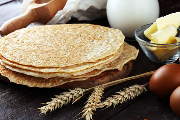 Homemade crepes served with fresh raspberrries and powdered sugar on rustic table.