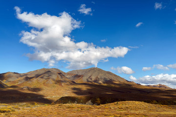 Fototapeta na wymiar Clouds over a peak on a tundra landscape with dramatic lighting with shadows at Denali National Park, Alaska