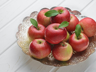 Red apples in an antique metal bowl. The concept of autumn harvest