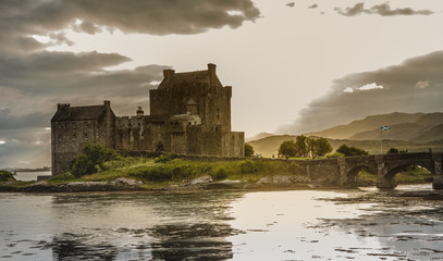 Naklejka na ściany i meble Eilean Donan Castle with cloudy sunset sky Highlands Scotland Landscape