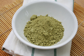 Green Matcha tea powder in a bowl on wooden background. Powdered matcha green tea on wooden table
