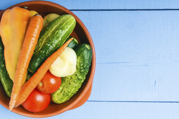 Organic natural cucumbers, tomatoes, carrots, bell pepper and onoin for vegetarian food. Rustic kitchen concept. Top view from above. Copy space
