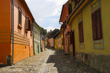 Fototapeta na wymiar Stone paved old streets with colorful houses in Sighisoara, Romania.