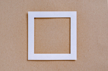 Fototapeta premium Empty white frame on a textured paper background, top view. Flat lay