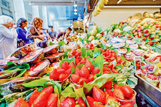 People making purchases in fruits department on food market in Barcelona.