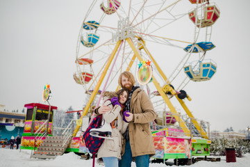 Young couple in love with a happy young man with a beard and a woman on a background of a fucking colossus, a Ferris wheel resting, a date in an amusement park in the winter in the Christmas holidays.