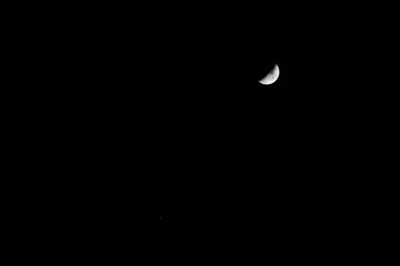 Crescent moon in the dark night with visible craters