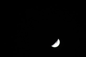 Crescent moon in the dark night with visible craters