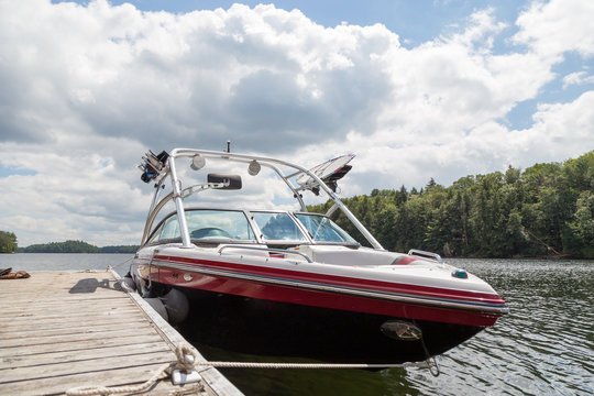 A Wakeboard Boat At A Wooden Dock In The Muskokas On A Sunny Day.