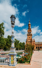 Naklejka premium Juxtaposition of blue and white ceramic azulejo tiles against one of the baroque sandstone tower at Plaza de Espana in Seville, Spain