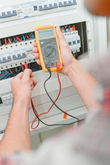 Man using multimeter on fusebox