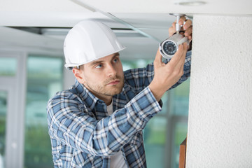 technician installing camera on wall using electric cordless drill