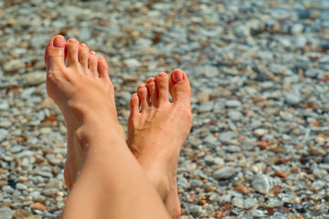 Female feet with a gentle pedicure on the background of the sea