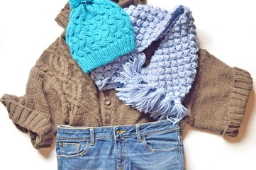Fall and winter fashion/ Flat lay photo winter outfit. Brown woolen sweater, blue jeans, knitted scarf and hat