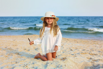Portrait of a cute little girl in a hat on the beach