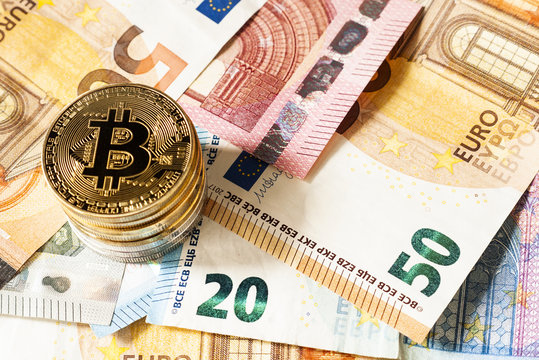 Golden Bitcoin coins on a background of Euro banknotes. 