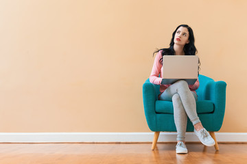 Young woman using her laptop on a blue chair