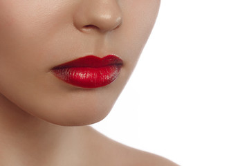 Cosmetics, makeup and trends. Bright lip gloss and lipstick on lips. Closeup of beautiful female mouth with red lip makeup. Beautiful part of female face. Perfect clean skin in red light © evgeniyasht19