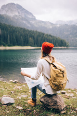 Woman traveler with backpack checks map 