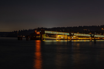 A long exposure of a ferry ramp at night with reflections in the water below