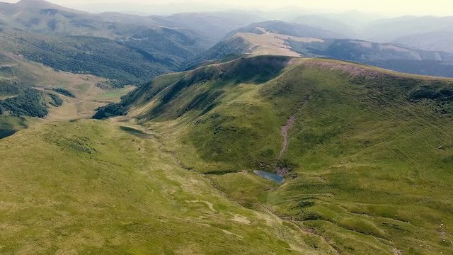 Aerial shot of a tiny pond at a sharp Carpathian Mountain foot in summer