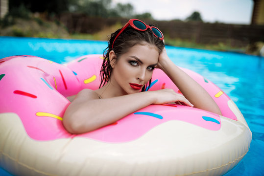 Beautiful sexy brunette girl in swimming pool on inflatable circle