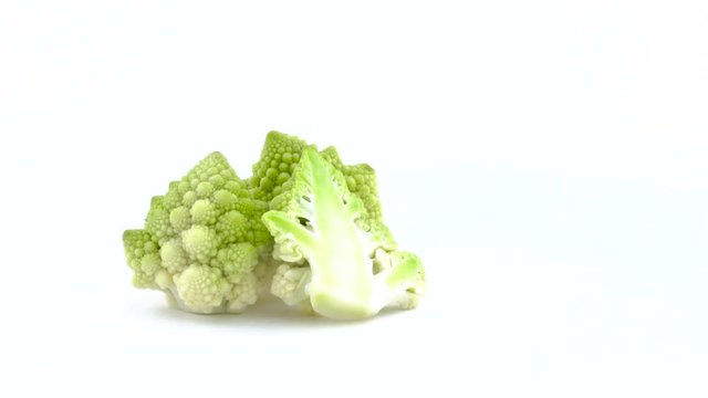 Half frame of two whole and one half of romanesco cauliflower are rotating on the turntable isolated on the white background. Close-up. Macro.
