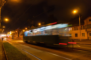 Fototapeta na wymiar The motion of a blurred tram down the street in the evening.