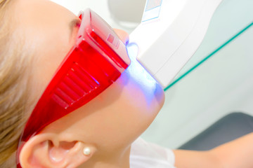 Naklejka premium Young woman having her teeth laser whitened