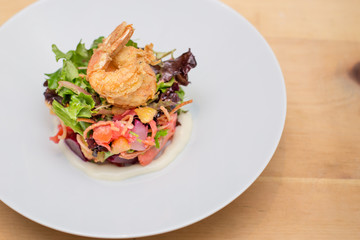 A prawn salad with beets on a white plate.