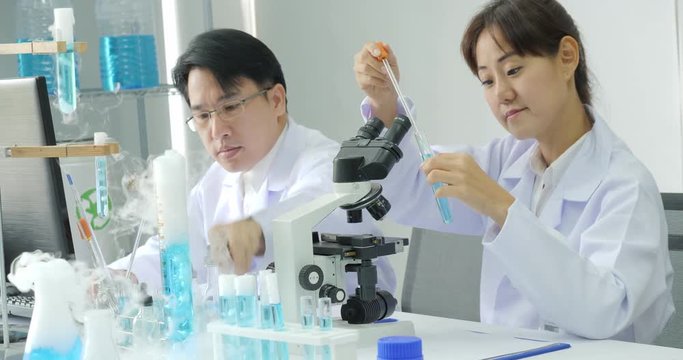Team of medical research scientists in laboratory looking through a microscope.