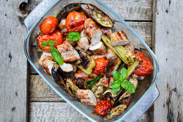 Juicy sausages and grilled vegetables in a glass bowl on a nature background. Dinner outdoors. Garden party. The top view