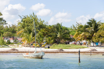 Old sail boat beside a tropical beach in Cancun, Mexico.