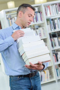 Man Carrying A Precarious Stack Of Books