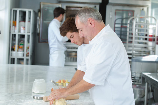 trainee chef wiping plate of gourmet dessert