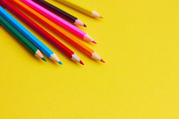 Colored pencils on a yellow background.