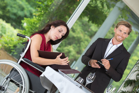 woman in wheelchair choosing the dish from the menu