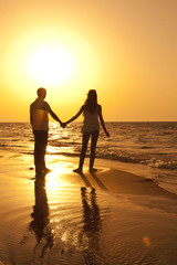 Romantic pair holding hands in the hot sunset