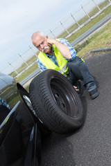 Obraz na płótnie Canvas discouraged retired man unable to change car tyre