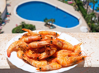 a plate with shrimps in front of the pool with blue water