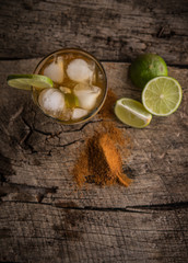 Top view of ice tea with lime and cinnamon over rustic wood