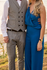 A girl in blue with a guy in a gray suit hugs against the sea