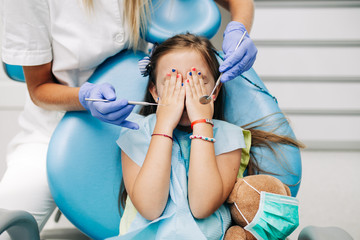 Cute little girl sitting on dental chair and having dental treatment.