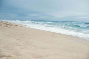 Blue ocean, blue skies and sand in the foreground