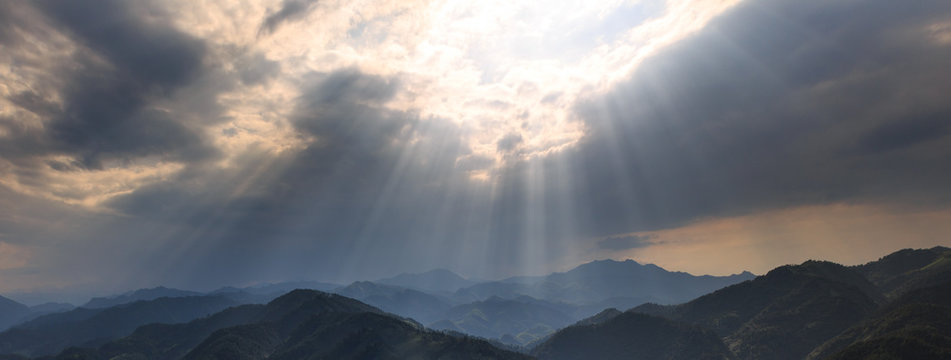 Rays of Sunshine Abstract Graphic Resource. Panoramic Mountains, Clouds and Bright Rays of Light Shining through an opening in the clouds. Sign from heaven concept, brilliant light from above.