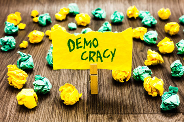 Writing note showing Demo Cracy. Business photo showcasing freedom of the people to express their feelings and beliefs Clothespin holding yellow note paper crumpled papers several tries.