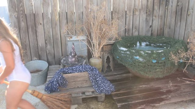Young girl is preparing to take part in celebration of Halloween. Child is bathing in cauldron with chamomile flowers, trying on pointed hat. She is ready to fly on broomstick like a witch.